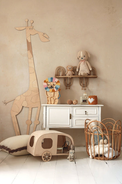 Natural wood giraffe wall decoration beside white dresser with shelves holding toys and nursery accessories