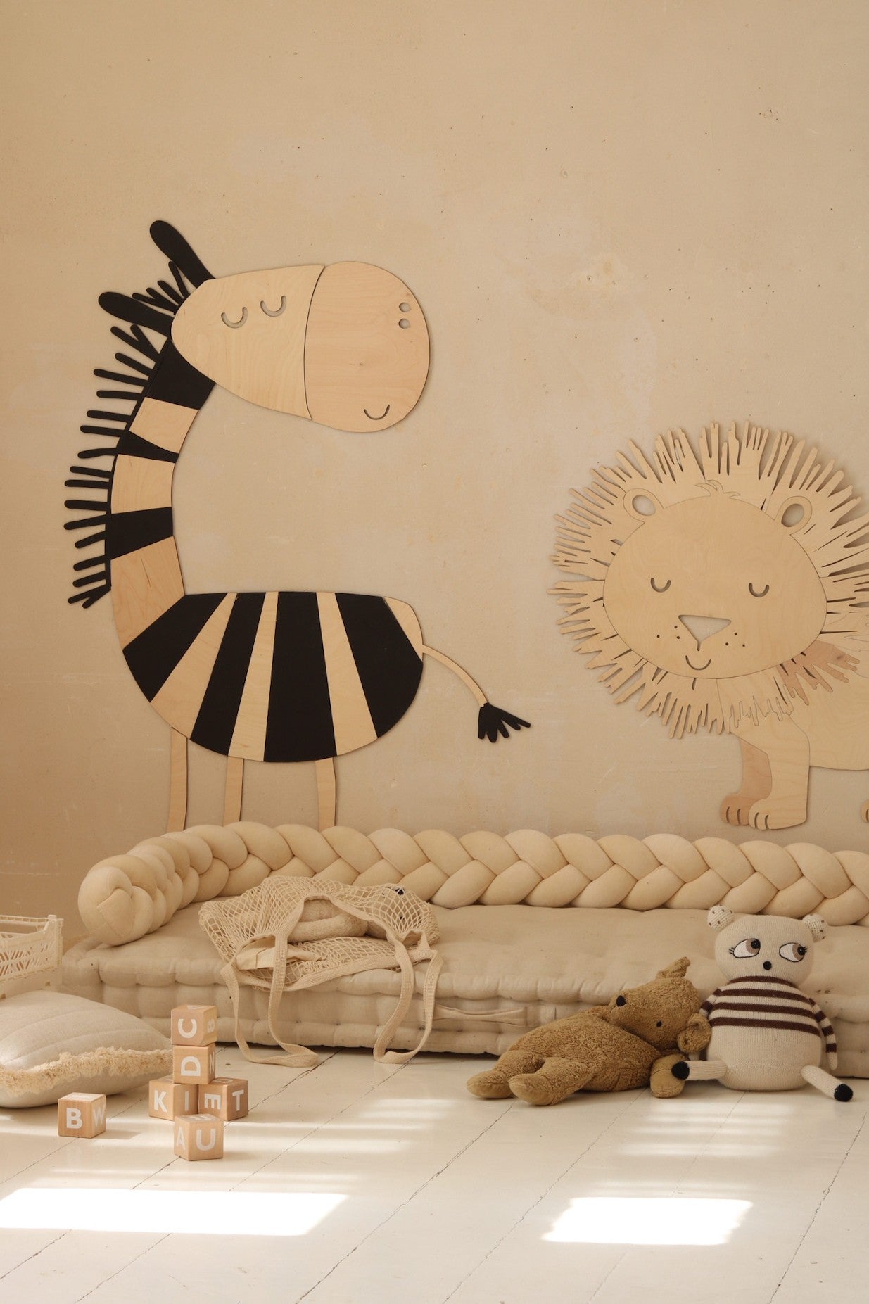 Black striped wooden zebra and lion wall decorations with playroom setup and toys
