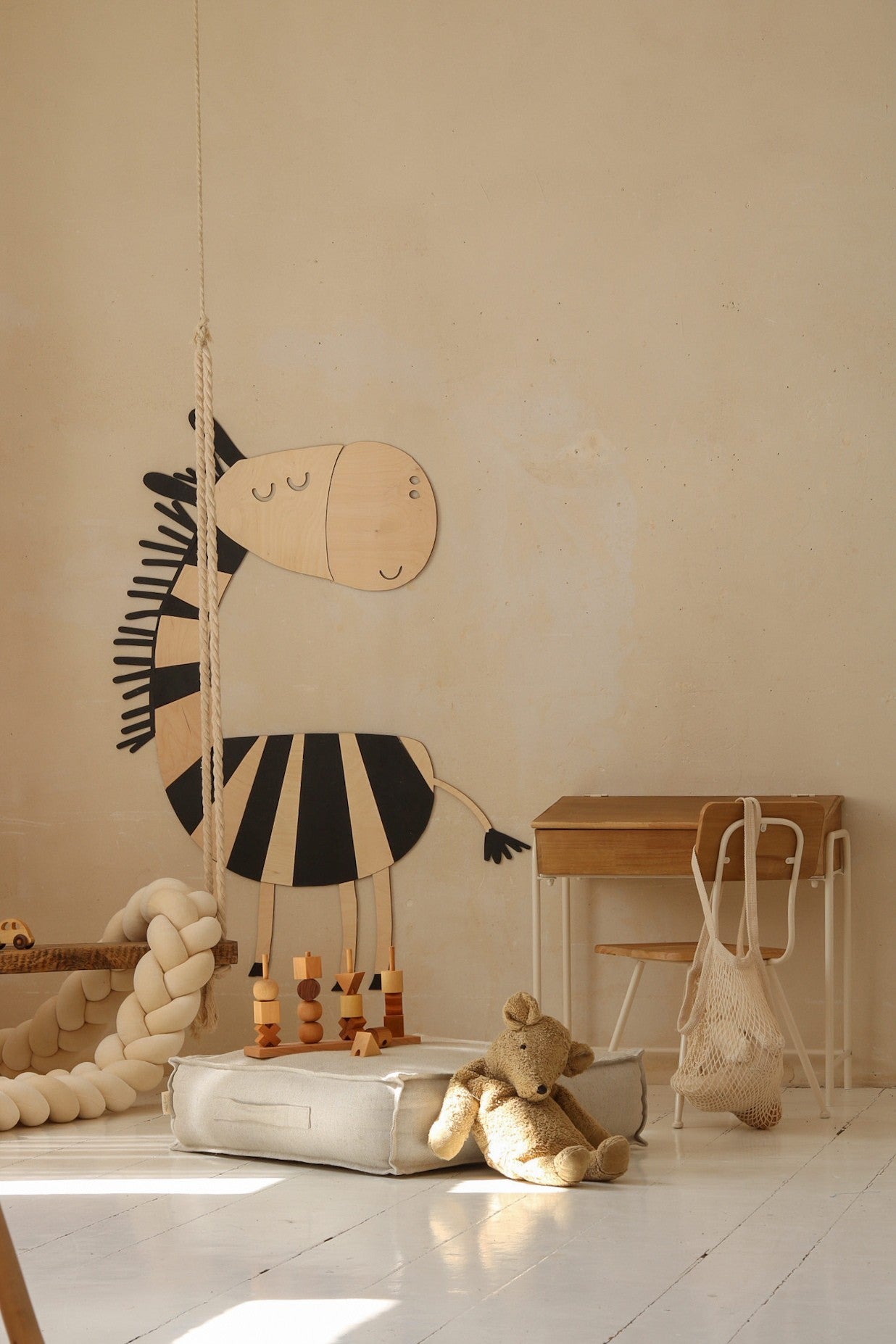 Wooden zebra wall decoration shown at an angle with children's furniture below