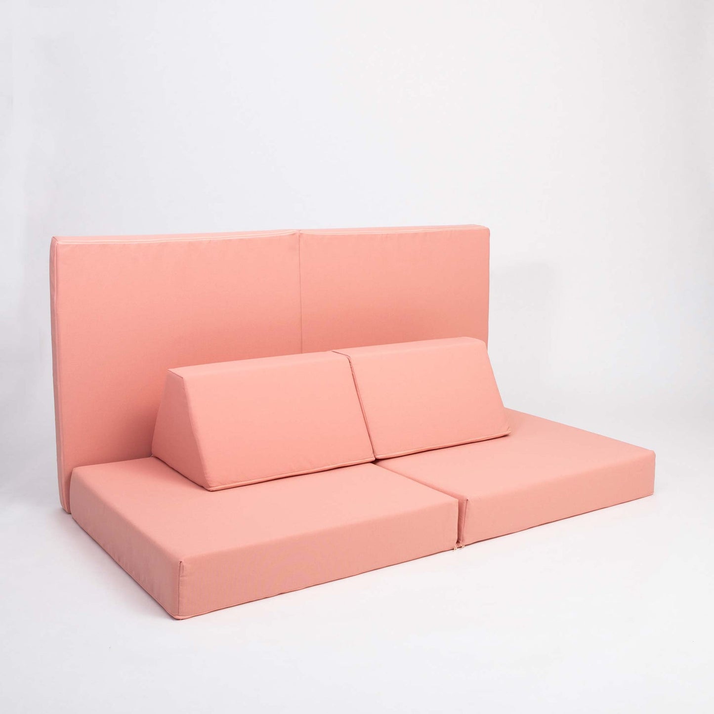 Salmon pink modular foam sofa set configured with back cushions and seat cushions