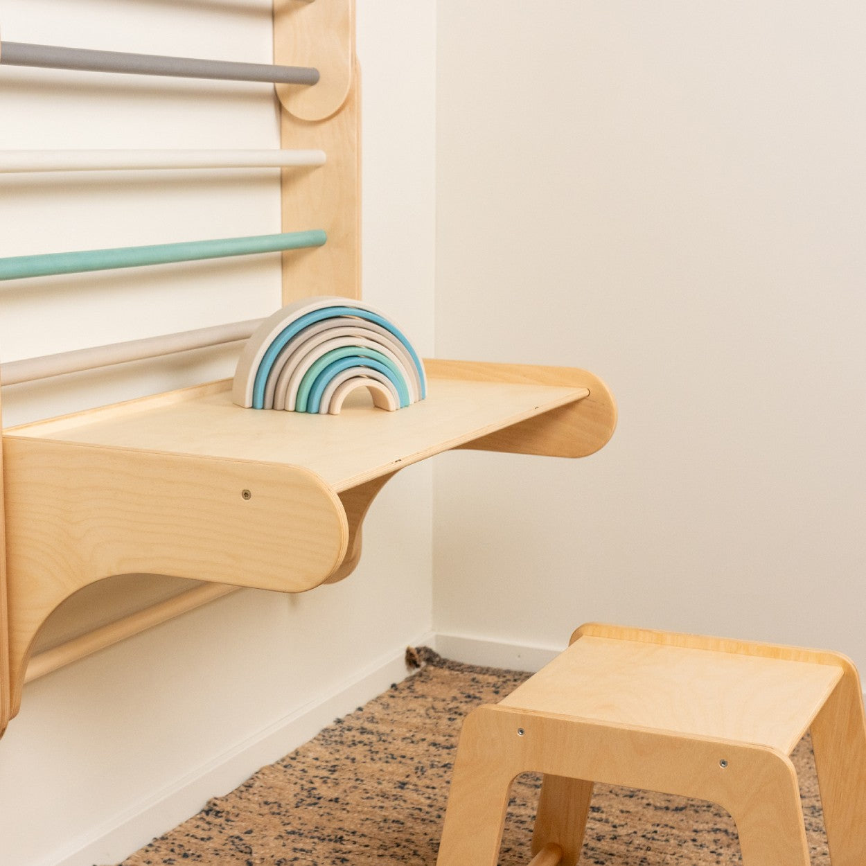 Wooden shelf bracket detail with rainbow toy storage on climbing wall desk