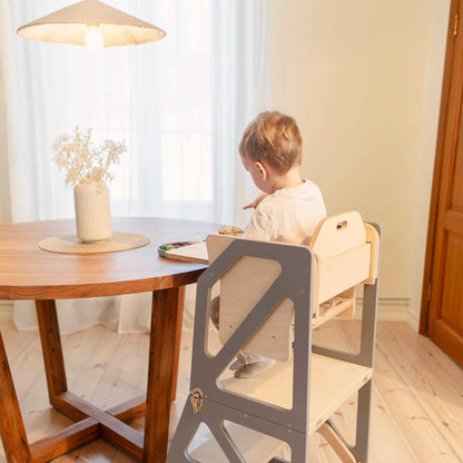 Toddler seated at dinner table in gray Modustep chair with wooden tabletop