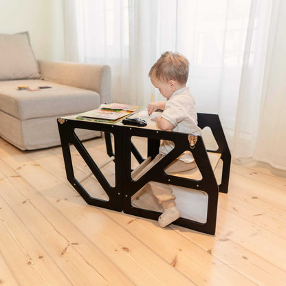 Toddler seated at low table using black Modustep chair in living space