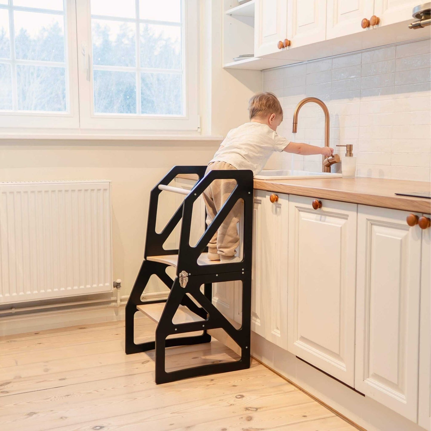 Toddler at faucet on black Modustep kitchen tower step stool