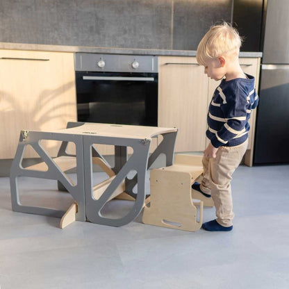 Toddler standing elevated at kitchen counter using beige learning tower