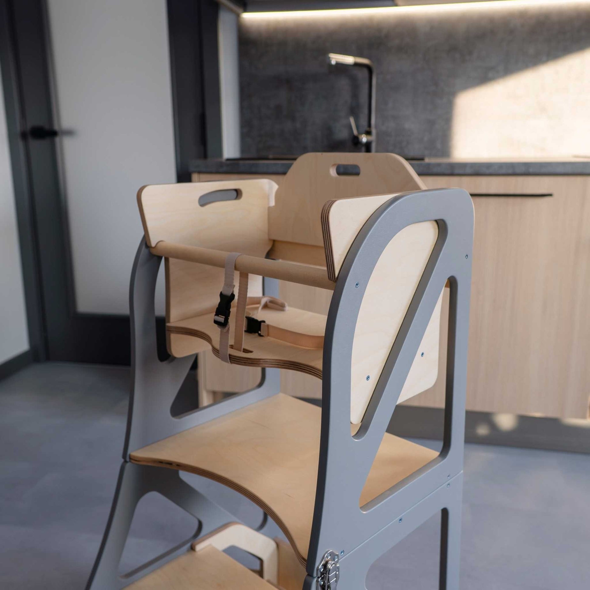 Child seated at integrated table on black kitchen tower with tray