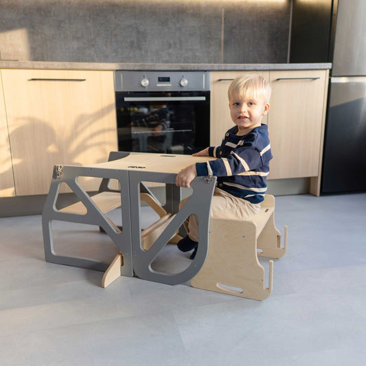 Toddler sitting at folded kitchen tower table and chair combo in kitchen