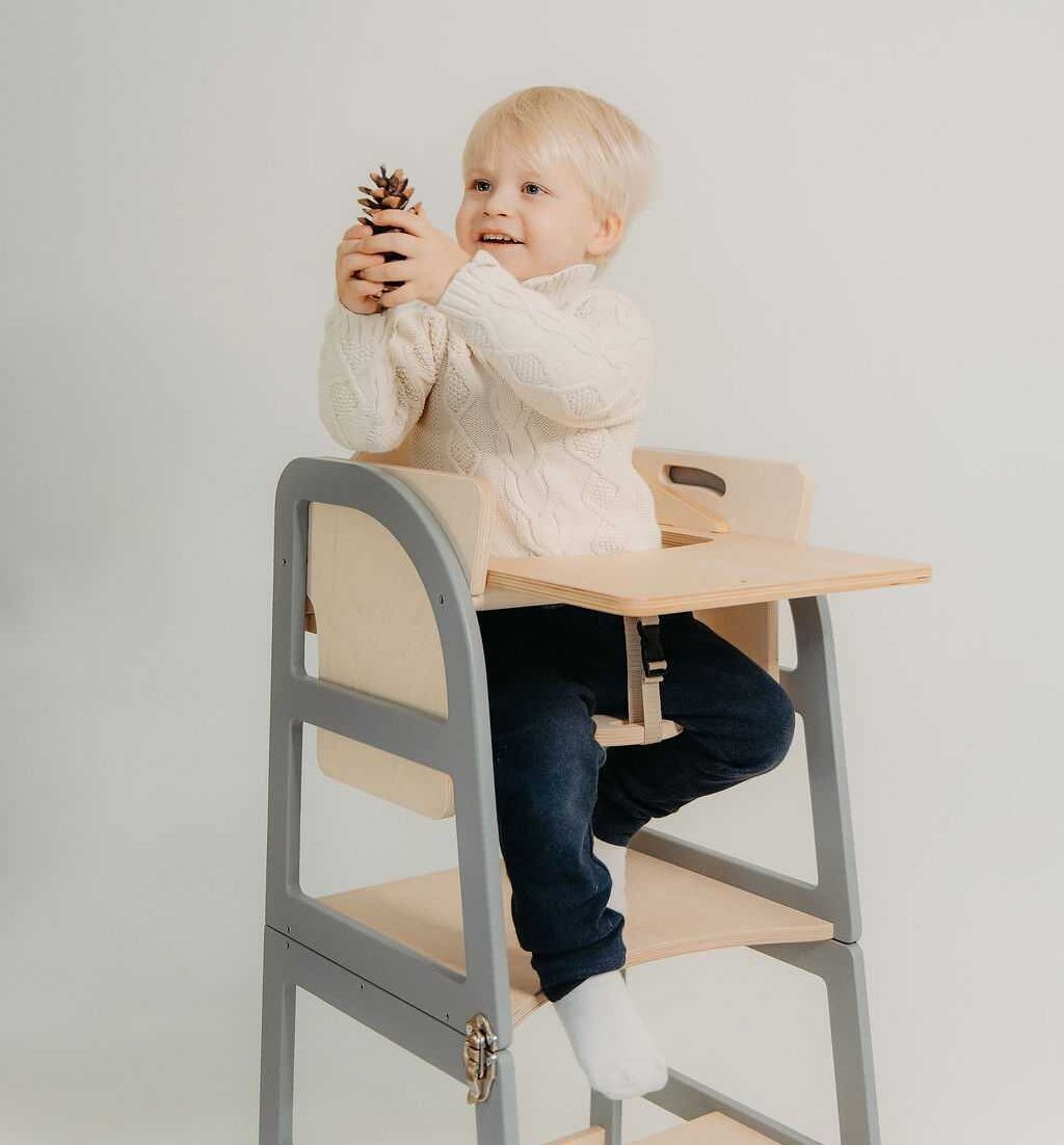 Small child seated at grey kitchen tower with attached wooden table