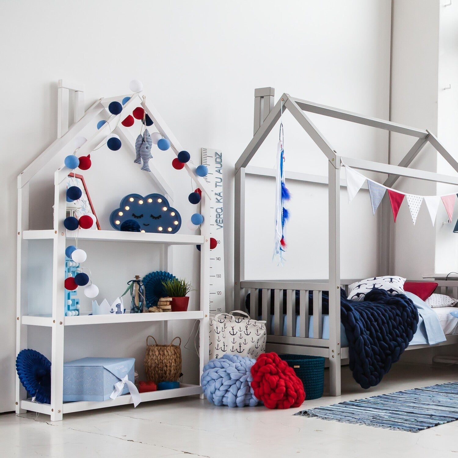 White house-shaped shelf with three shelves holding books, decor, and toys in nursery