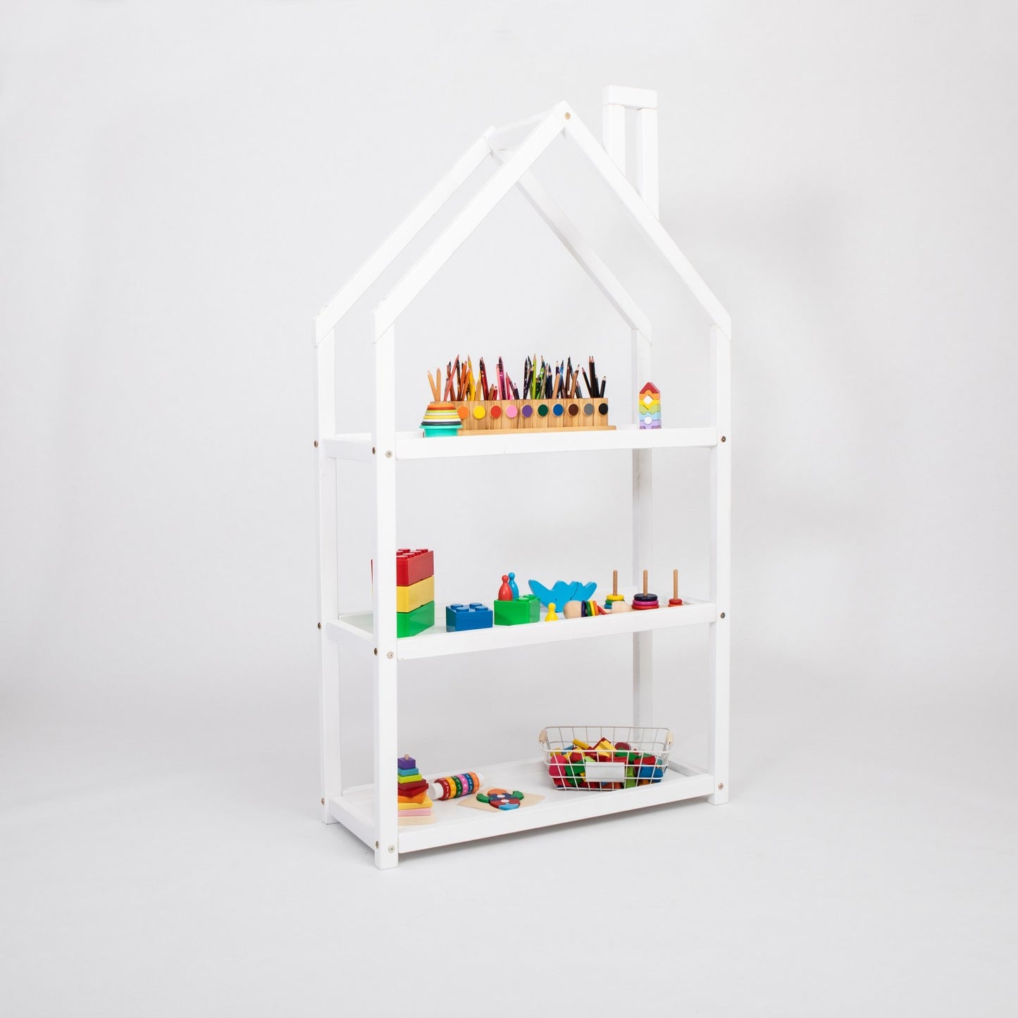 White house-shaped shelf with colored pencils, blocks, and toys on display