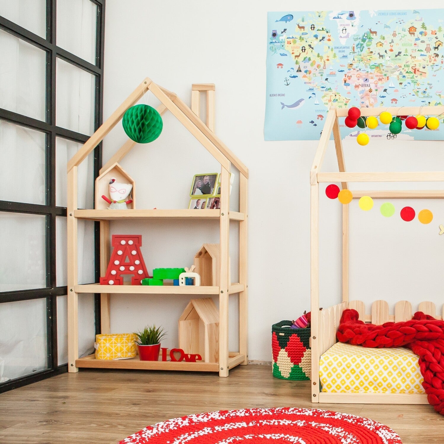 Natural wood house shelf with three shelves displaying books and toys in playroom