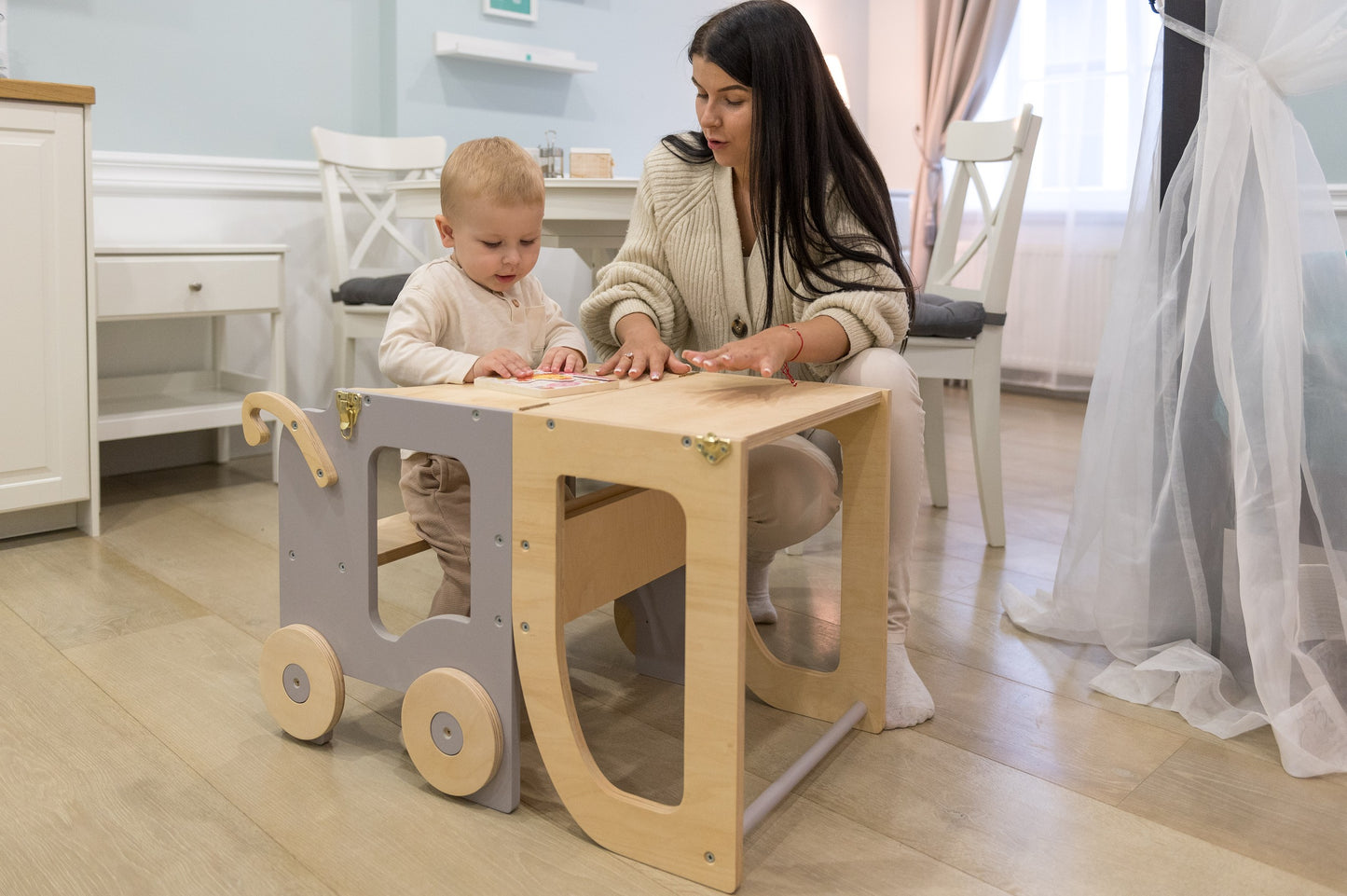 Toddler standing on Family-scl learning tower helping with cooking in modern kitchen