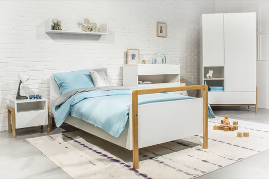 Victor children's bed in white with oak legs displayed in bright nursery room with matching furniture