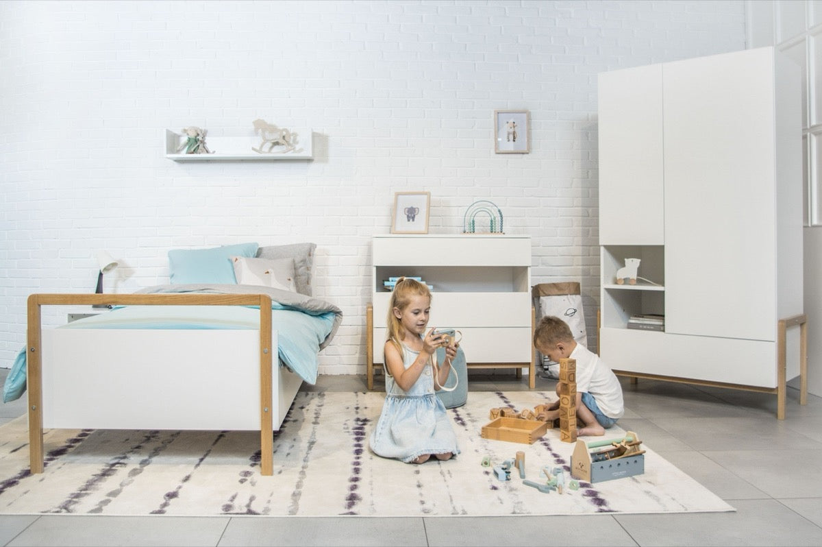 Two children playing beside Victor Scandinavian kids bed in white with oak accents in modern bedroom