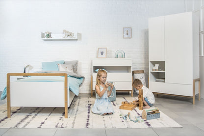 Two children playing beside Victor Scandinavian kids bed in white with oak accents in modern bedroom