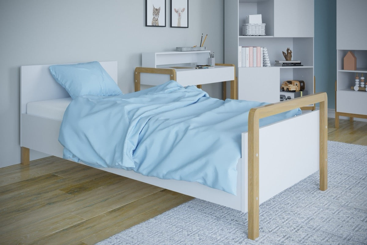 Victor children's bed with light blue bedding positioned next to white desk and storage shelving