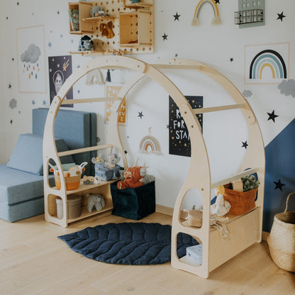 Montessori house bed with open shelving inside playroom near wall art and storage baskets