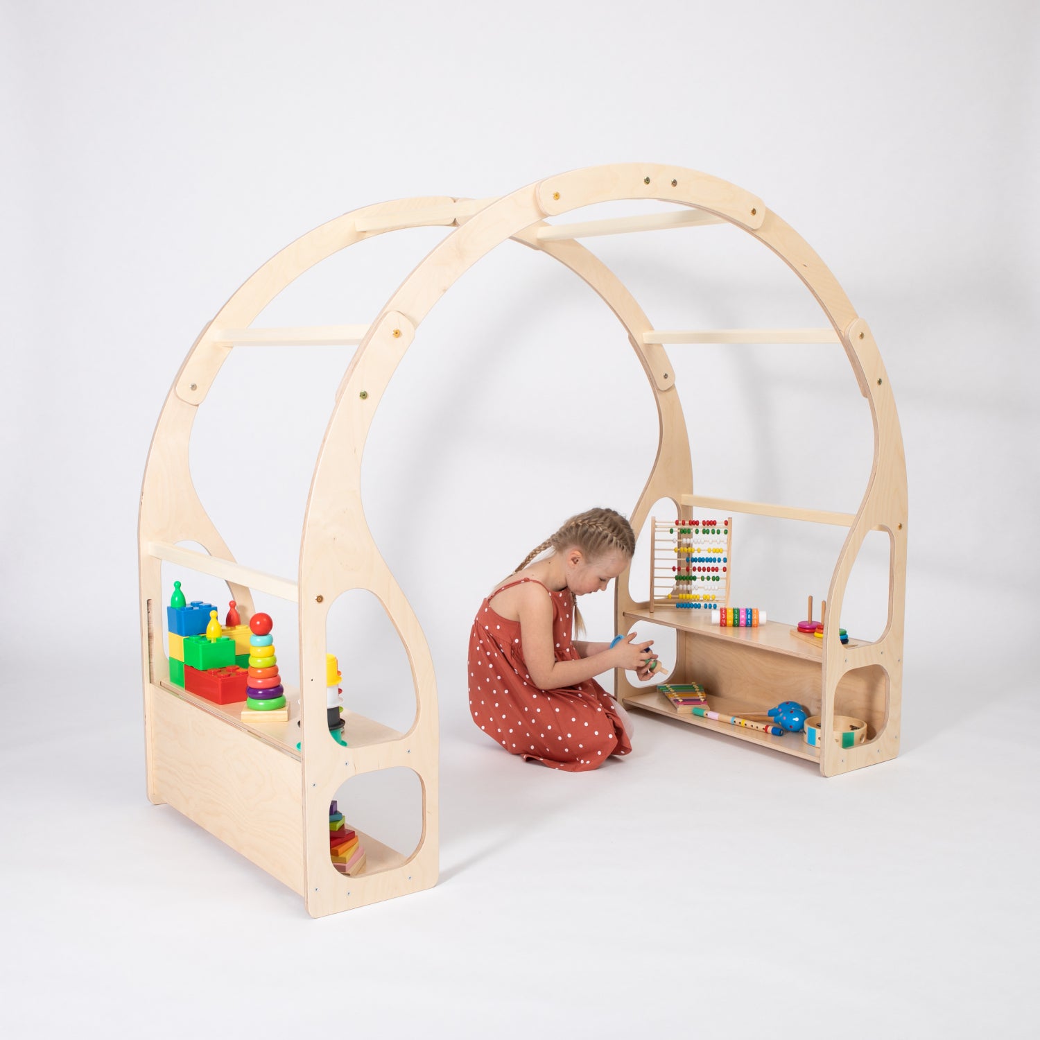 Toddler using wooden play stand as pretend kitchen with toys and activity storage