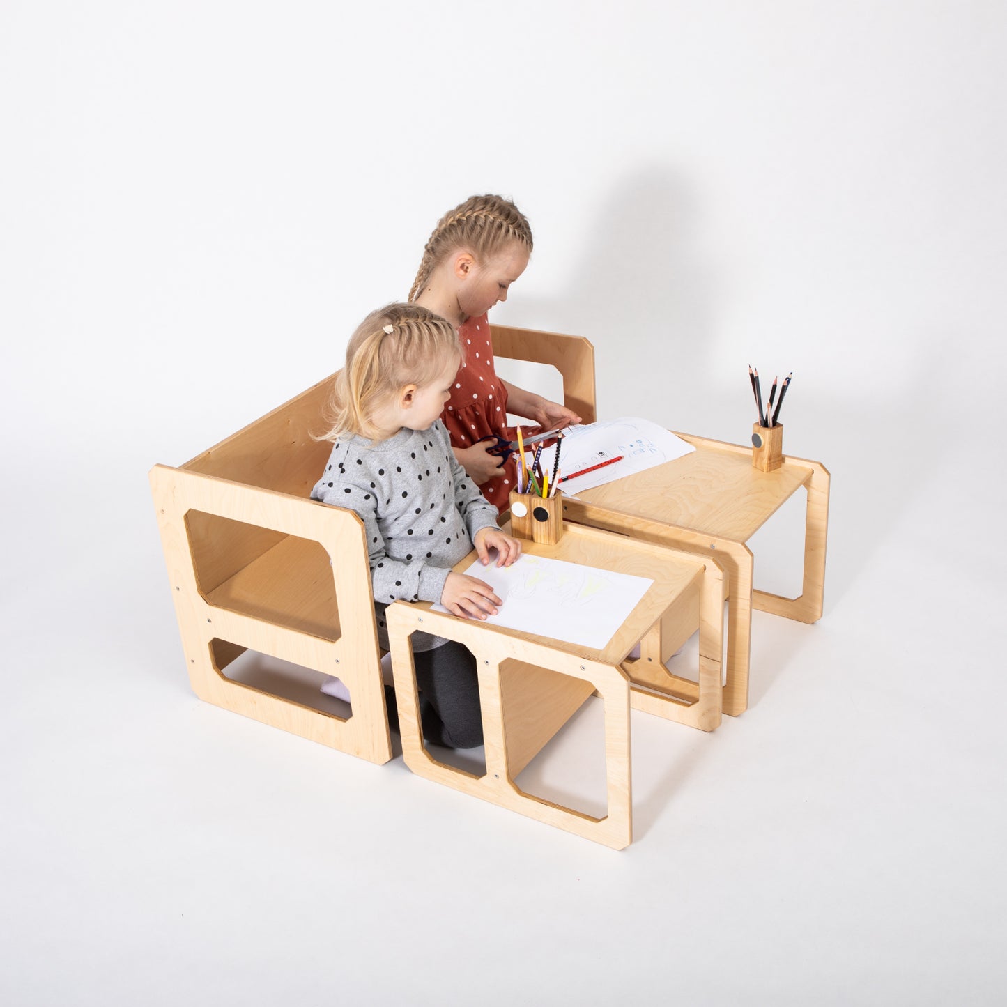 Two toddlers drawing and playing at natural wood Montessori table with two matching chairs