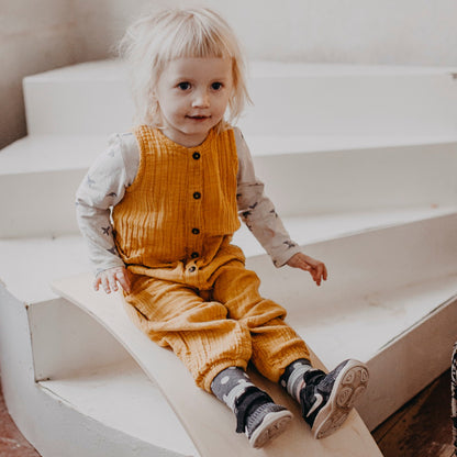 Young child sitting on wooden balance board used as a seat for open-ended play