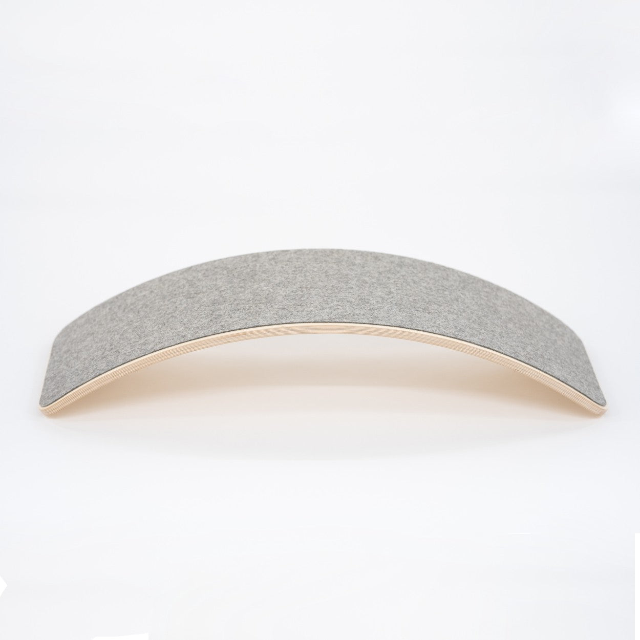 Wooden balance board with grey felt top surface, curved design side view