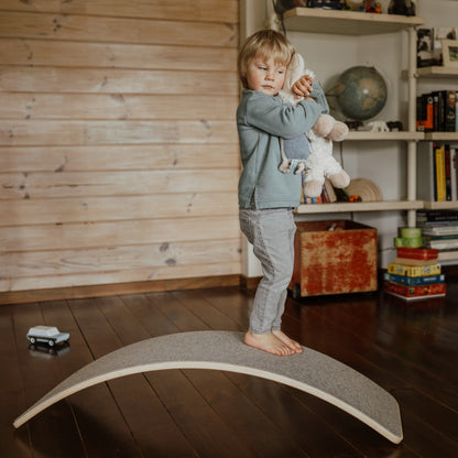 Toddler standing on balance board working on coordination and gross motor skills