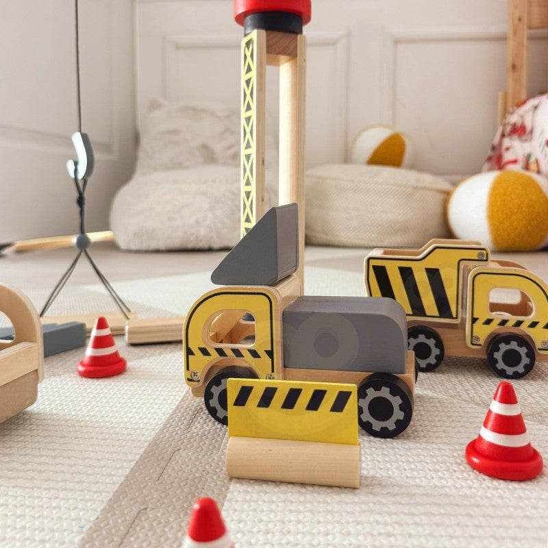 Wooden construction vehicles and traffic cones arranged around base of rotating crane toy