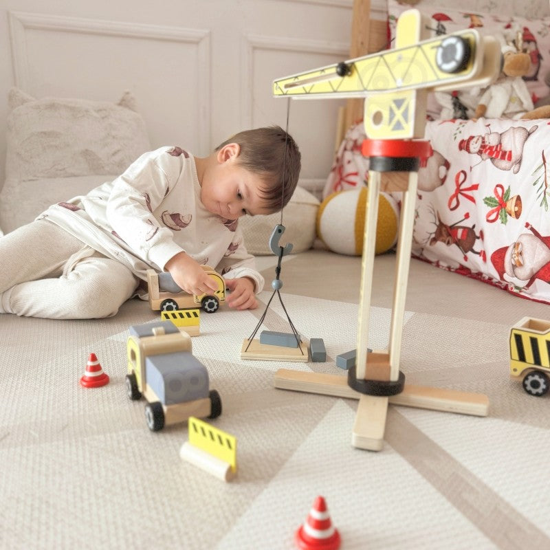Child operating wooden crane to lift construction materials during imaginative play session