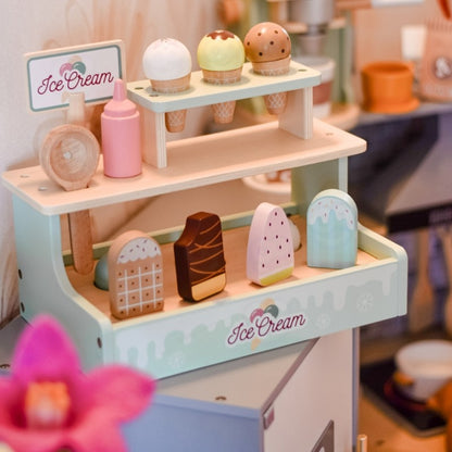 Wooden ice cream shop set on desk with blurred home interior and plant in background