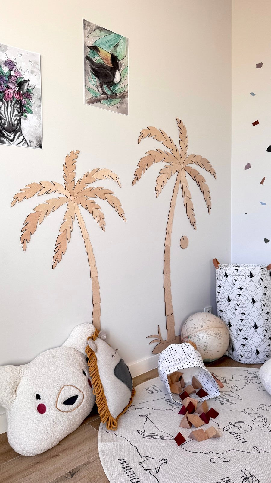 Pair of wooden palm tree wall decor mounted on beige wall above playroom accessories