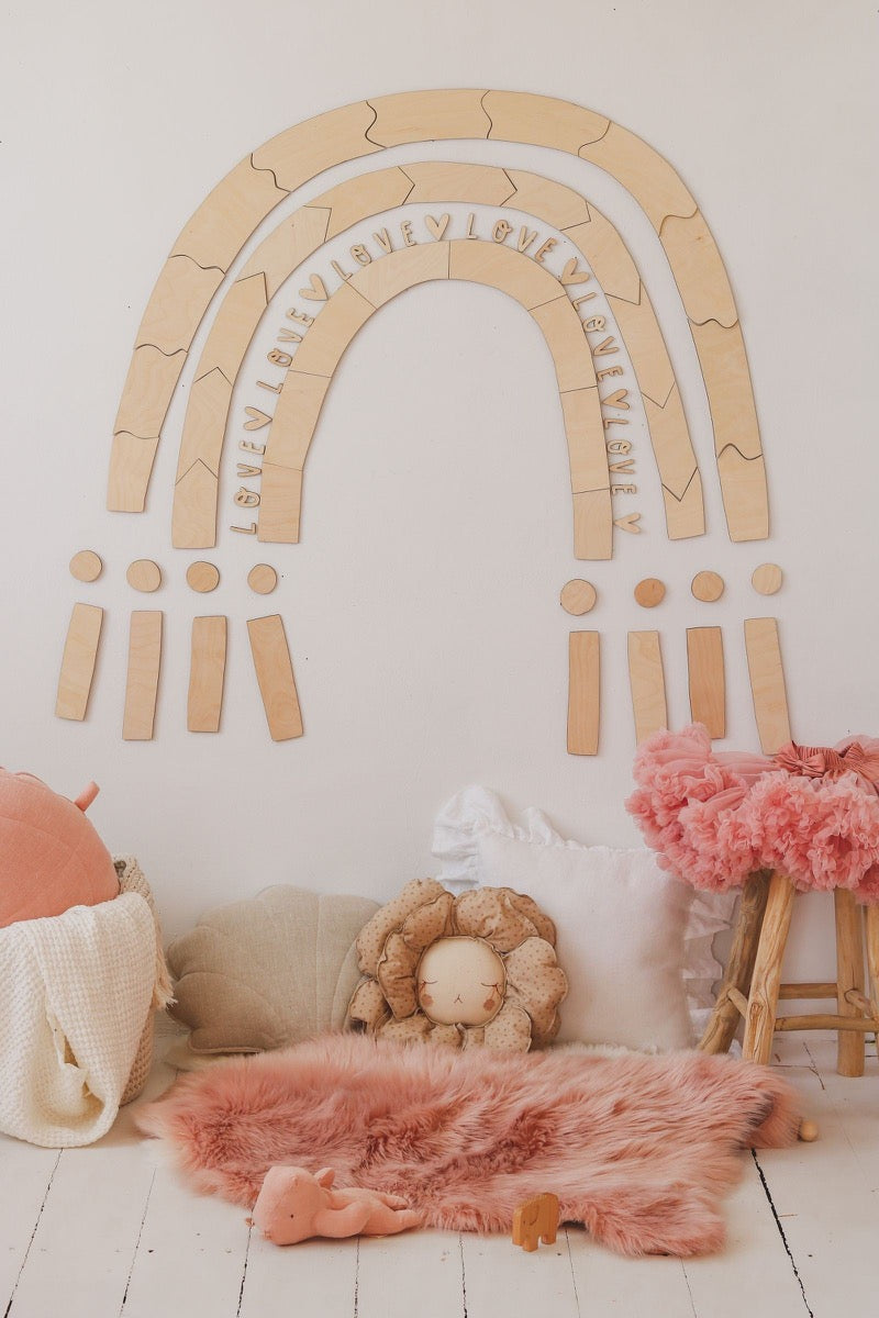 Flat lay of assembled rainbow wall art with pink accents and woven basket accessories