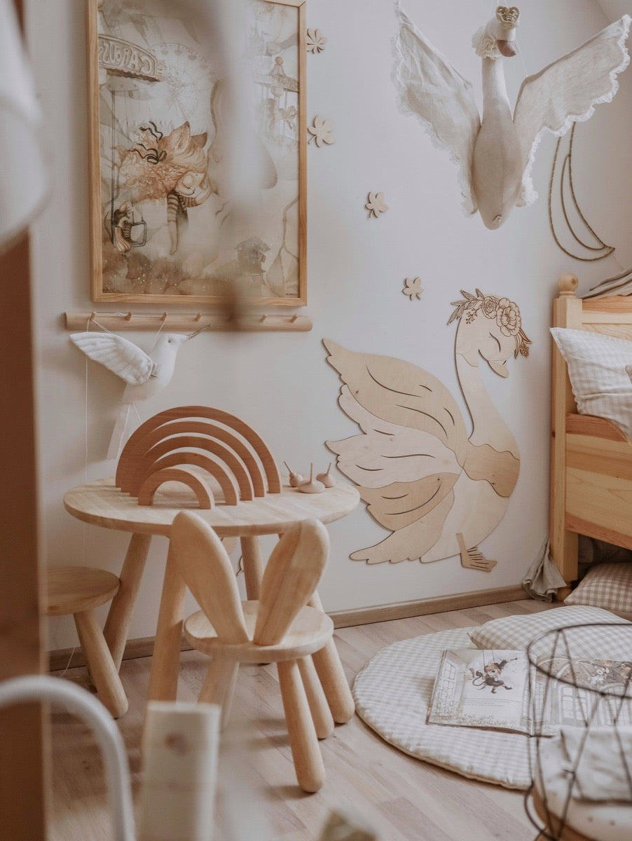 Birch plywood swan wall decoration installed in playroom above wooden table and children's furniture