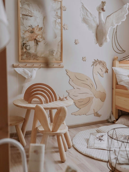 Birch plywood swan wall decoration installed in playroom above wooden table and children's furniture