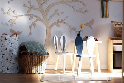 Birch plywood tree with birds wall decor displayed in a modern playroom with white chairs and natural light