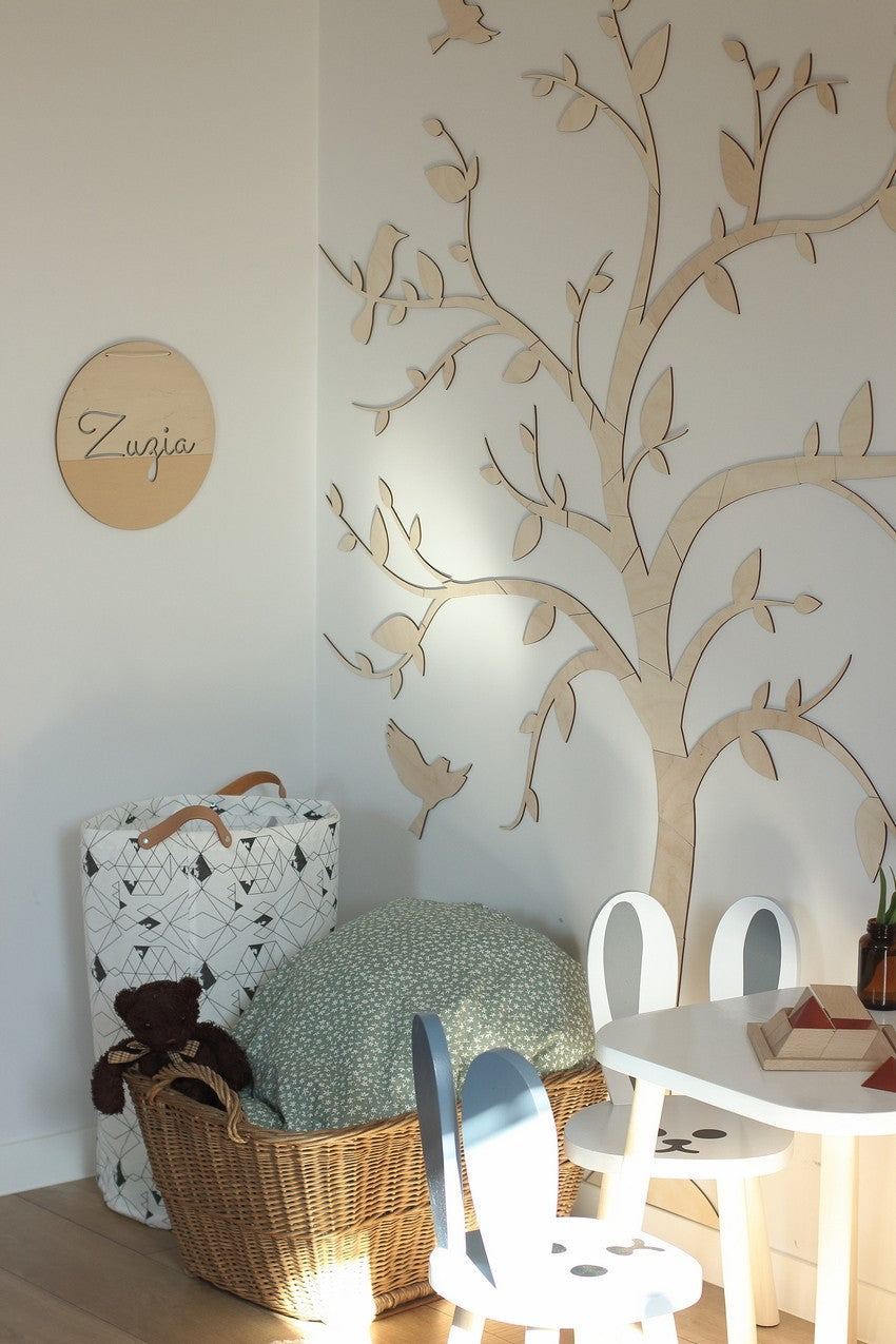 Tree with birds wooden wall decoration beside a personalized wooden sign in a styled kids bedroom