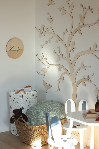 Tree with birds wooden wall decoration beside a personalized wooden sign in a styled kids bedroom