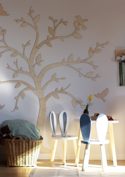 Wooden tree wall decoration with bird cutouts lit by warm lighting in a contemporary nursery space