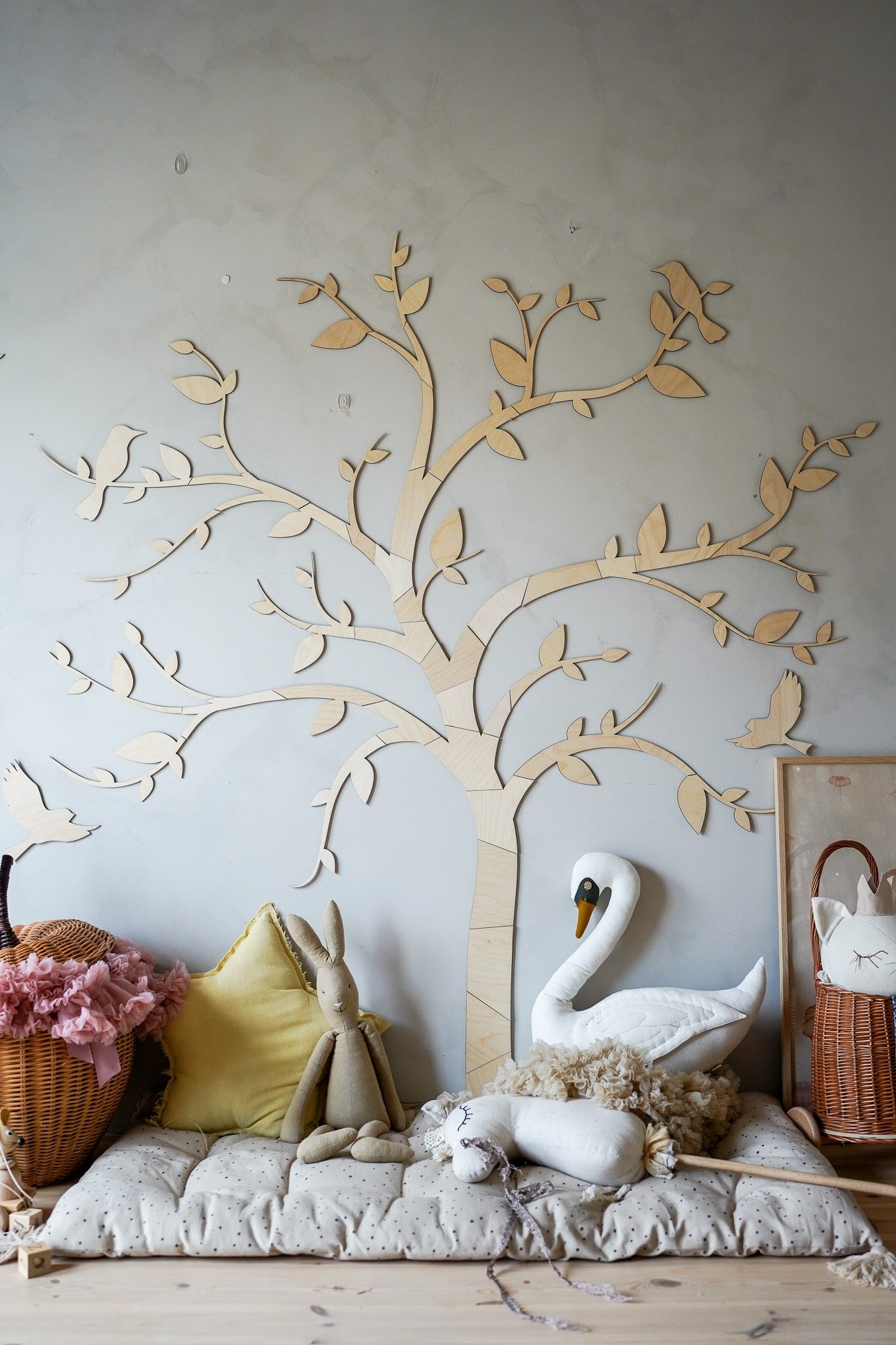 Birch plywood tree with birds wall decor above cushions and decorative items in a child's room