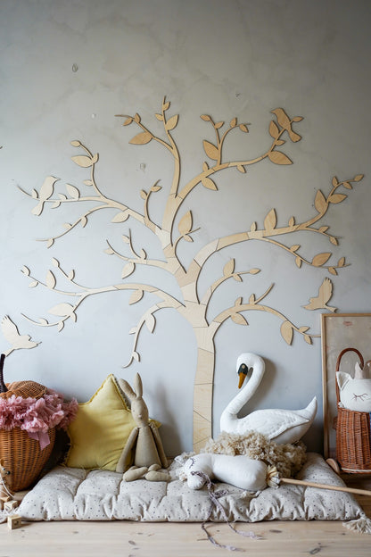 Birch plywood tree with birds wall decor above cushions and decorative items in a child's room