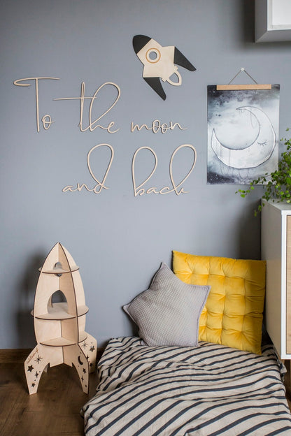 Close-up of To the Moon and Back plywood sign showing handcrafted lettering and rocket design